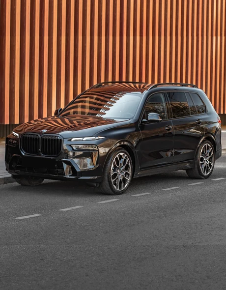 Чёрный BMW X7 xDrive 40 припаркован у дизайнерской стены – премиальный внедорожник в аренду от SK CARS в Варшаве.