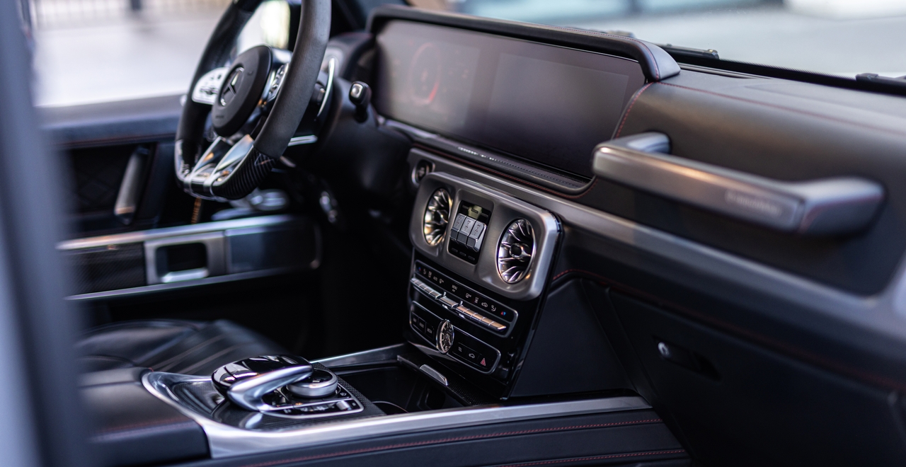 Центральная консоль Mercedes-AMG G63 с двойным дисплеем, фирменными дефлекторами и кнопками блокировок дифференциалов — всё под рукой, всё под контролем.