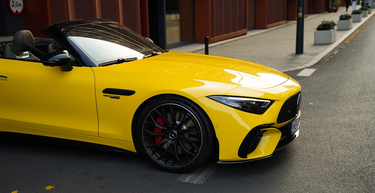 Mercedes SL55 AMG — жёлтый кабриолет, вид сбоку спереди, выделяющийся тормозными суппортами и значком V8 Biturbo