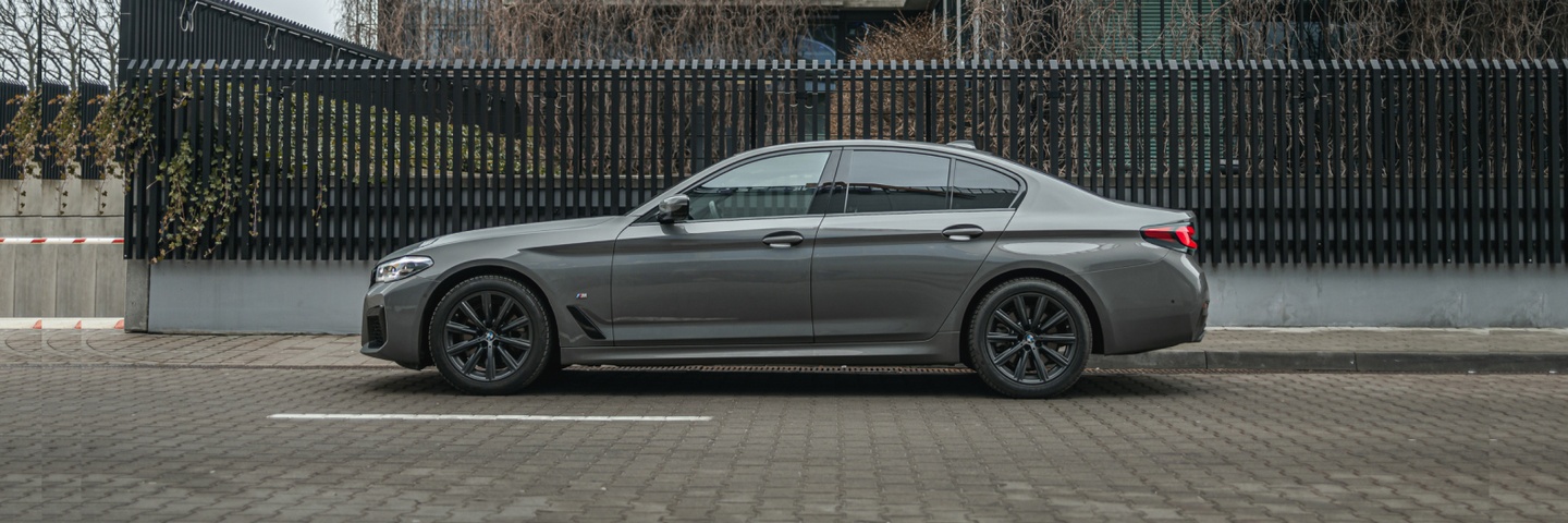 Серый BMW 5 серии, вид сбоку, демонстрирующий элегантность и мощь. Забронируйте этот автомобиль в SK CARS для уникального опыта вождения.