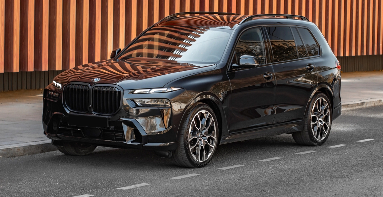 Чёрный BMW X7 xDrive 40 припаркован у дизайнерской стены – премиальный внедорожник в аренду от SK CARS в Варшаве.